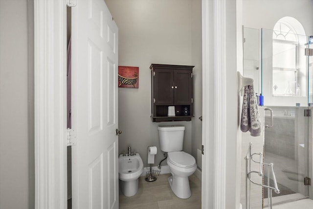 bathroom with toilet, a shower with shower door, and a bidet