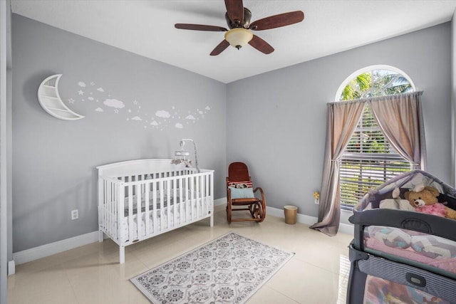 tiled bedroom featuring a crib and ceiling fan