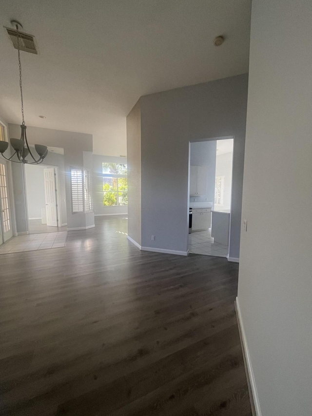 spare room featuring dark hardwood / wood-style flooring and a chandelier