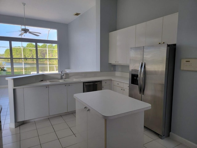 kitchen with a center island, sink, stainless steel appliances, light tile patterned floors, and white cabinets