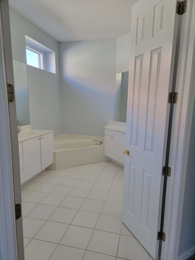 bathroom featuring tile patterned floors, a bathtub, a textured ceiling, and vanity