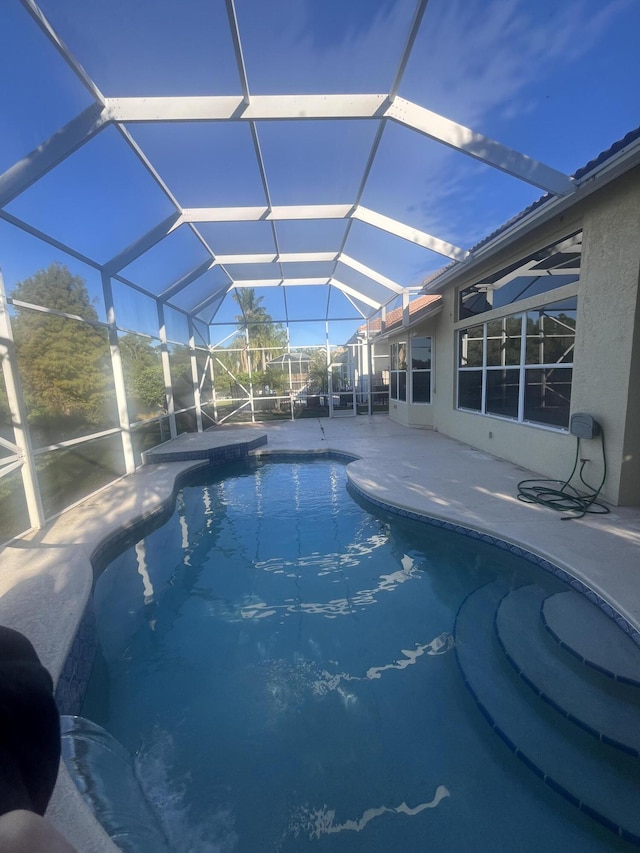 view of swimming pool with glass enclosure and a patio area