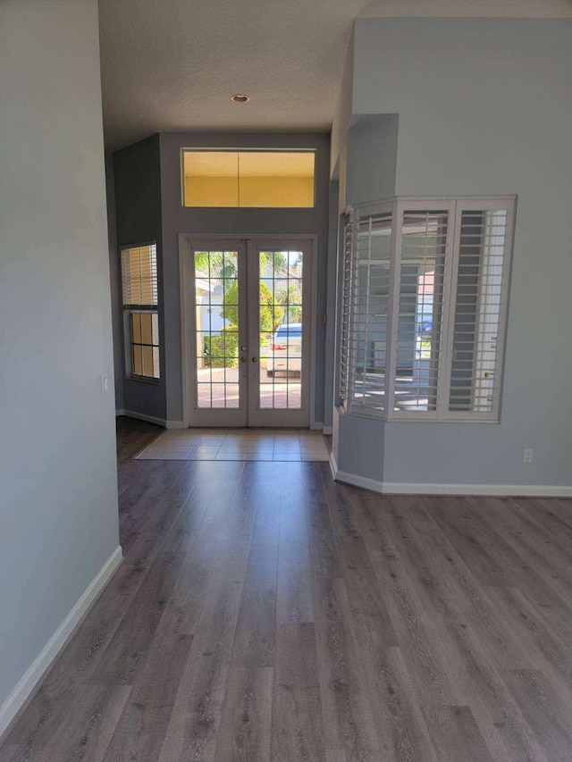 foyer entrance with french doors, a textured ceiling, hardwood / wood-style flooring, and vaulted ceiling