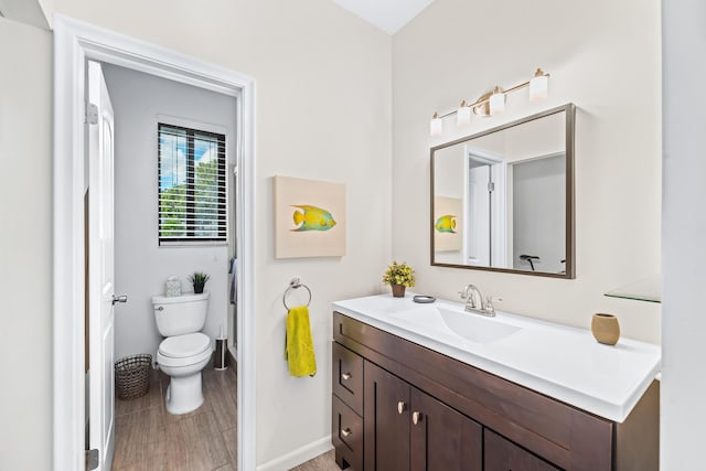 bathroom with hardwood / wood-style flooring, vanity, and toilet