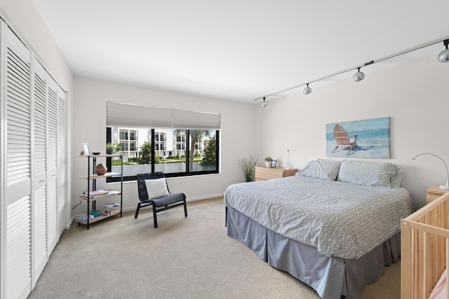 carpeted bedroom with a closet and rail lighting