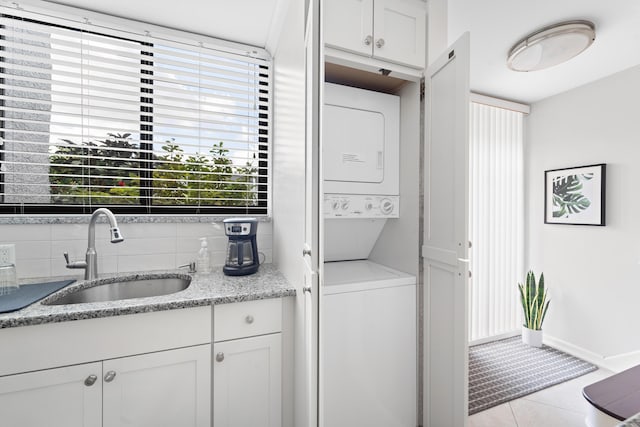 laundry room with stacked washer / drying machine, light tile patterned floors, and sink