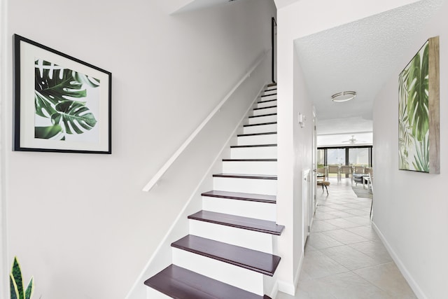 stairway featuring tile patterned floors and a textured ceiling