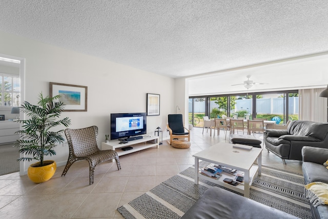 living room featuring ceiling fan, light tile patterned flooring, and a textured ceiling