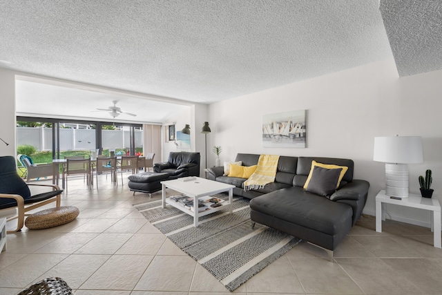 living room with ceiling fan, light tile patterned floors, and a textured ceiling