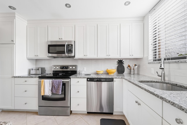 kitchen with white cabinets, sink, light stone countertops, and stainless steel appliances