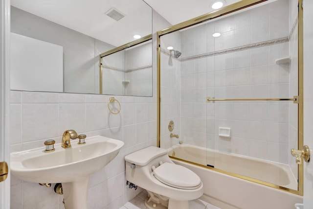 bathroom with shower / bath combination with glass door, tile walls, and toilet