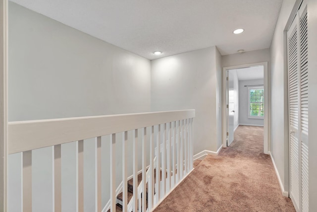 corridor featuring a textured ceiling and light colored carpet