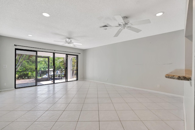 spare room with ceiling fan, light tile patterned floors, and a textured ceiling