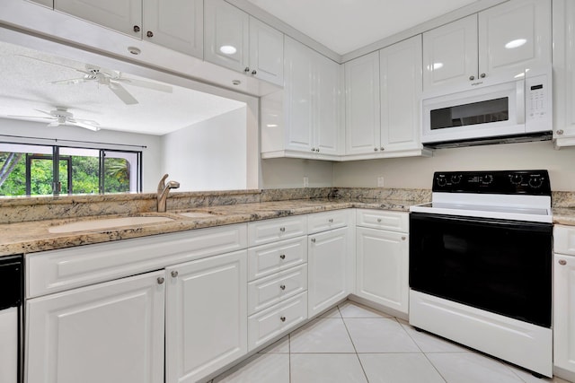 kitchen with range with electric cooktop, light stone counters, sink, light tile patterned floors, and white cabinetry