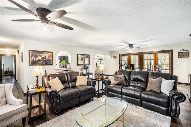 living room with a textured ceiling, dark hardwood / wood-style flooring, and ceiling fan