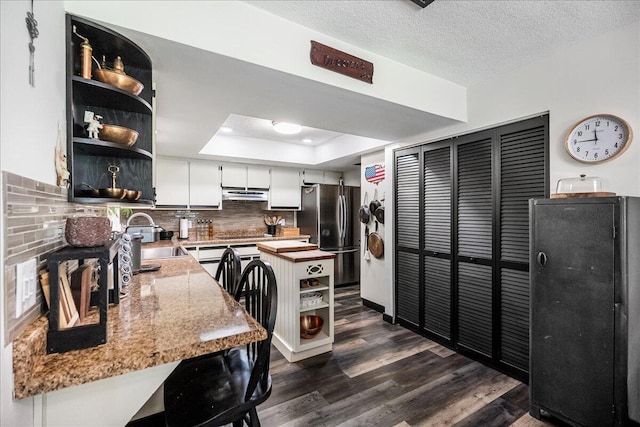 kitchen featuring white cabinetry, sink, dark hardwood / wood-style flooring, backsplash, and stainless steel fridge