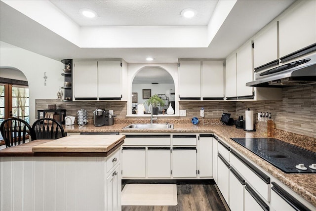 kitchen with black electric stovetop, dark hardwood / wood-style flooring, ventilation hood, sink, and white cabinets