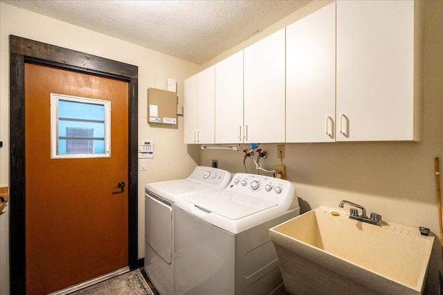 washroom featuring separate washer and dryer, sink, cabinets, and a textured ceiling