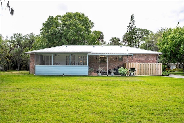 rear view of house featuring a sunroom and a lawn