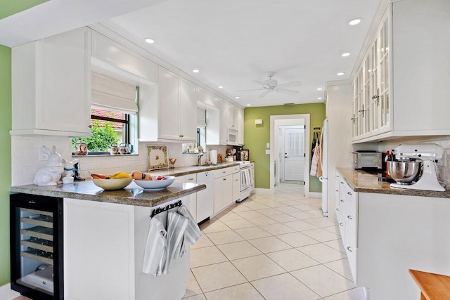 kitchen with backsplash, wine cooler, white cabinetry, and white appliances