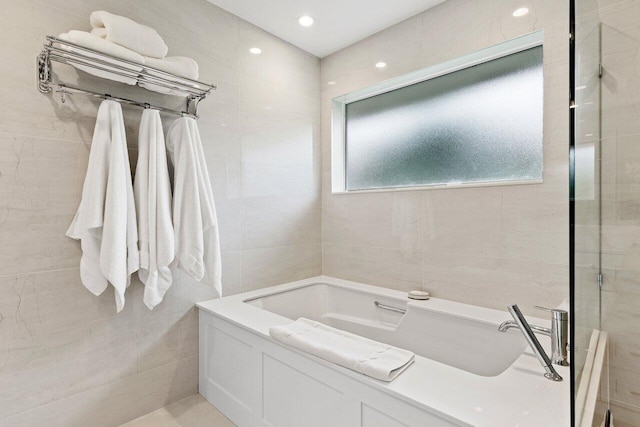 bathroom featuring a washtub and tile walls