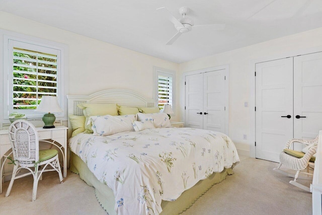 bedroom with multiple closets, ceiling fan, and light carpet