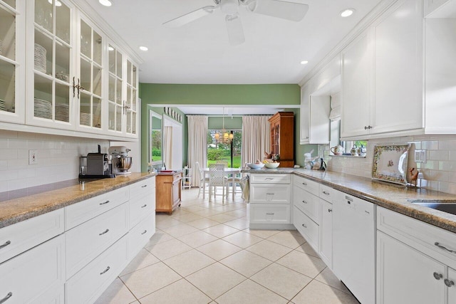 kitchen featuring white cabinetry, dishwasher, tasteful backsplash, light stone counters, and light tile patterned floors