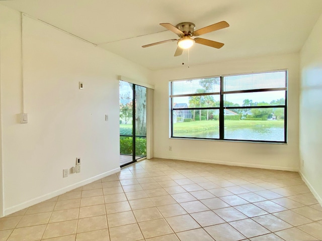 unfurnished room with ceiling fan, light tile patterned flooring, and a water view