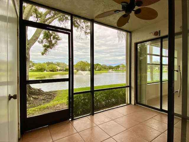 unfurnished sunroom featuring ceiling fan and a water view