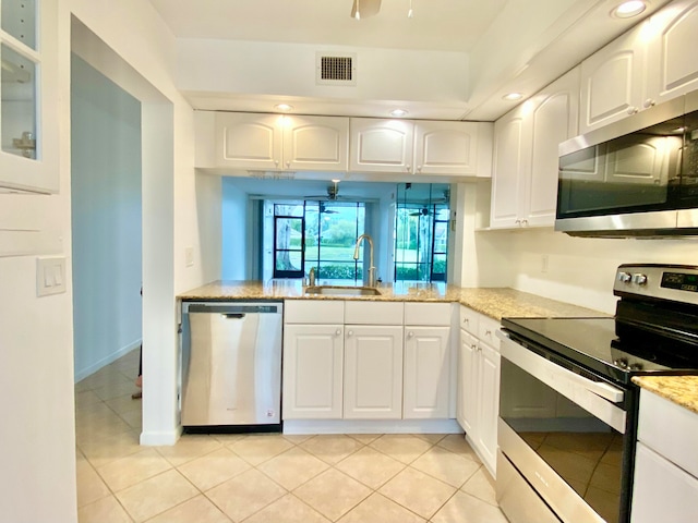 kitchen featuring light stone countertops, white cabinetry, sink, stainless steel appliances, and light tile patterned floors