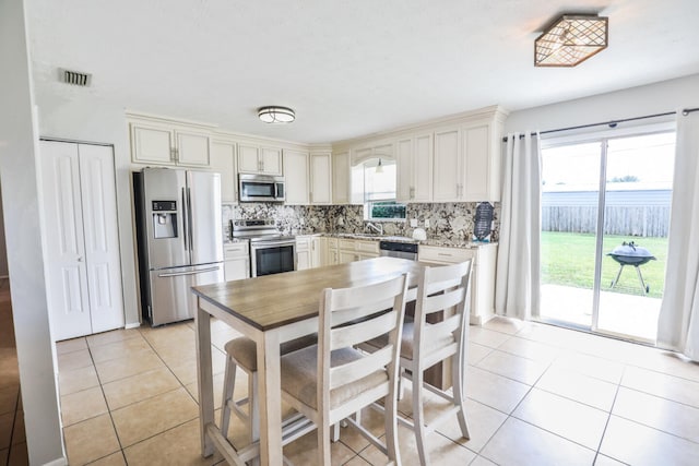 kitchen with decorative backsplash, appliances with stainless steel finishes, and light tile patterned flooring