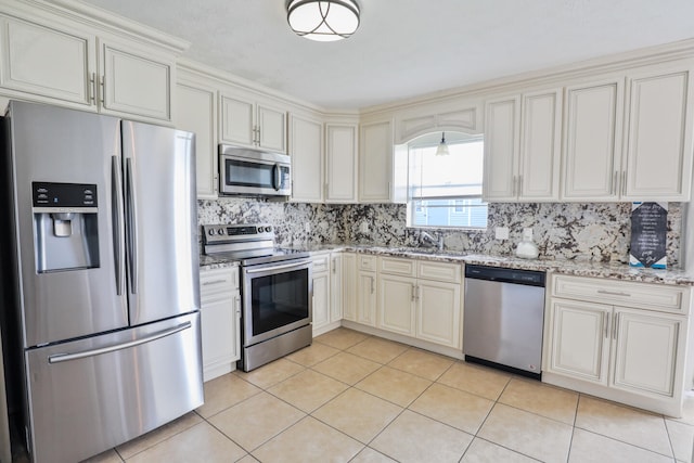 kitchen featuring sink, decorative backsplash, light tile patterned floors, appliances with stainless steel finishes, and light stone counters