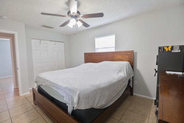 bedroom with ceiling fan, light tile patterned flooring, and a closet