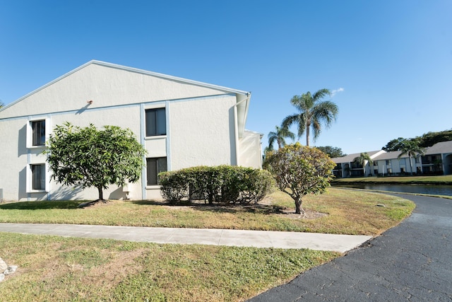 view of side of home featuring a lawn, a water view, and stucco siding