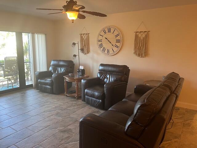 living area with baseboards and ceiling fan