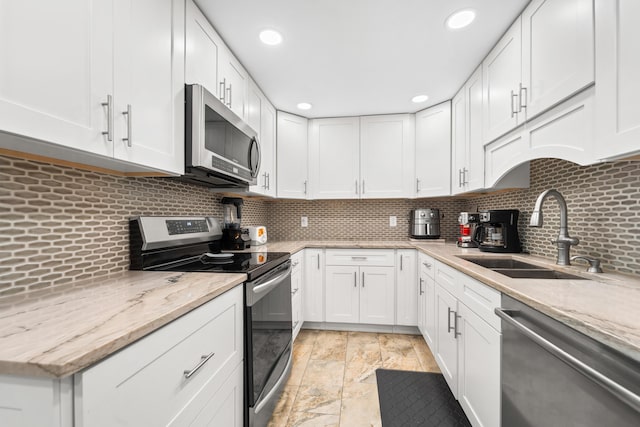 kitchen featuring a sink, backsplash, appliances with stainless steel finishes, and white cabinets