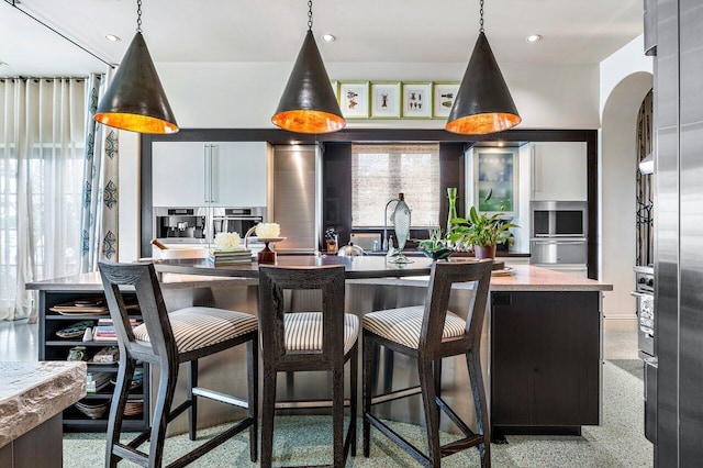 kitchen with a center island, decorative light fixtures, light stone counters, and stainless steel oven