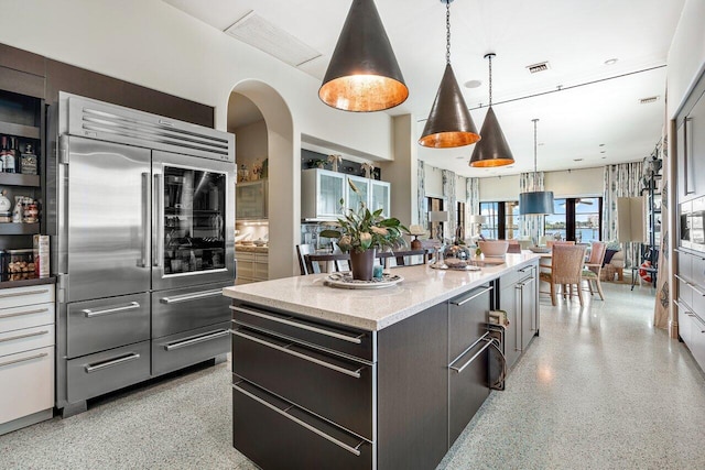813 N Atlantic Dr, Lantana, FL 33462 - kitchen with built in fridge, dark aggregate flooring, a center island, decorative light fixtures, and light stone countertops