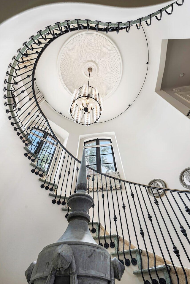 staircase with a high ceiling and a notable chandelier