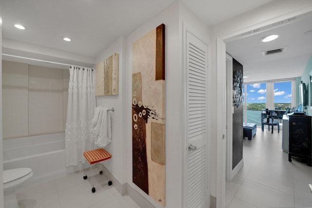 bathroom with shower / bathtub combination with curtain, toilet, a water view, and a wall of windows