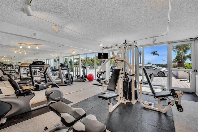 workout area with a textured ceiling and a wall of windows