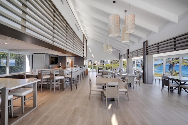 dining area featuring ceiling fan, a towering ceiling, a healthy amount of sunlight, and light wood-type flooring