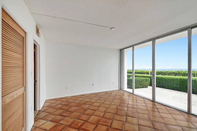 tiled empty room with floor to ceiling windows and a textured ceiling