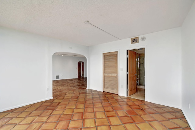 unfurnished room with light tile patterned floors and a textured ceiling