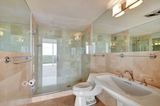 bathroom featuring a shower with door, sink, tile patterned flooring, toilet, and tile walls