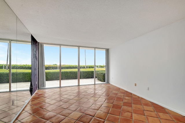 unfurnished room with tile patterned flooring, floor to ceiling windows, and a textured ceiling