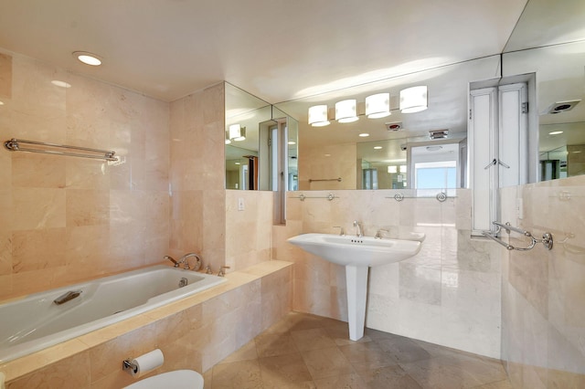 bathroom with tile patterned flooring, a relaxing tiled tub, tile walls, and sink