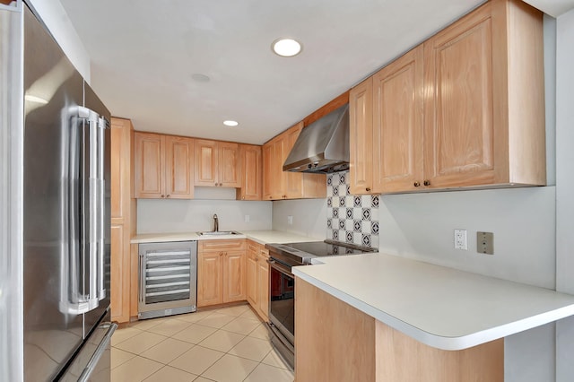 kitchen featuring wall chimney range hood, sink, light brown cabinetry, stainless steel appliances, and beverage cooler