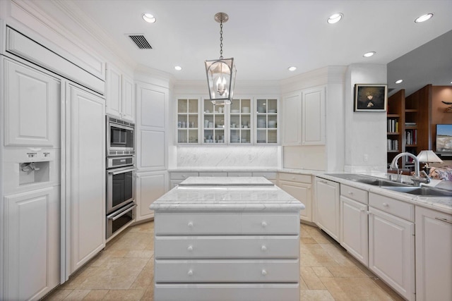 kitchen with sink, built in appliances, a center island, white cabinetry, and hanging light fixtures