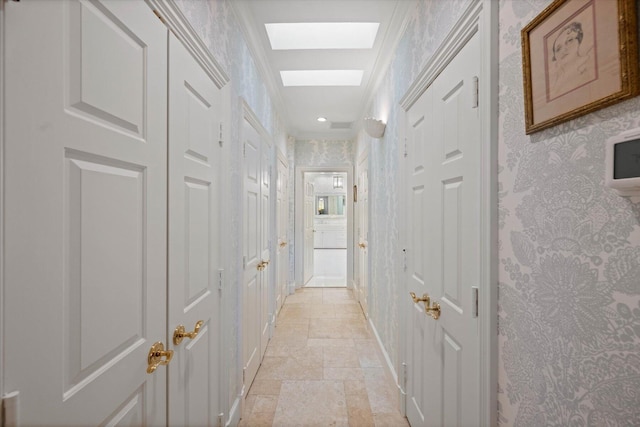 hallway with ornamental molding and a skylight